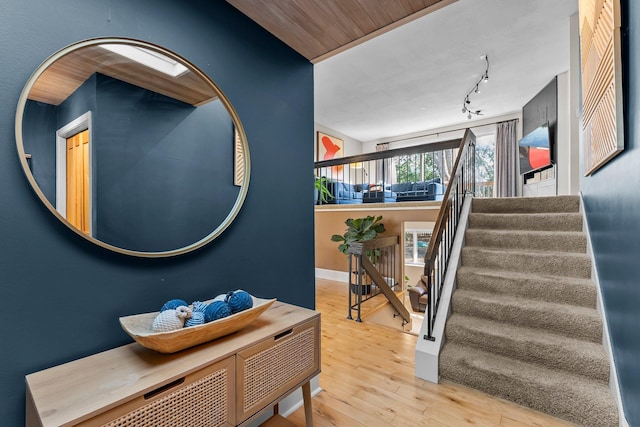 entryway featuring rail lighting, stairs, baseboards, and wood-type flooring