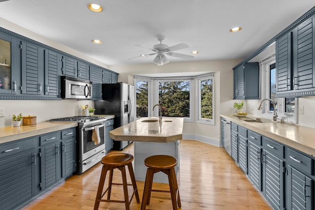 kitchen with a sink, a kitchen breakfast bar, light wood-type flooring, and stainless steel appliances