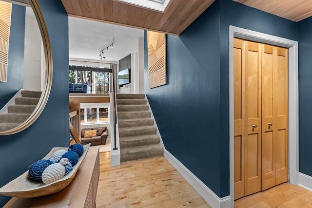 stairway featuring track lighting, baseboards, wood ceiling, a skylight, and wood-type flooring