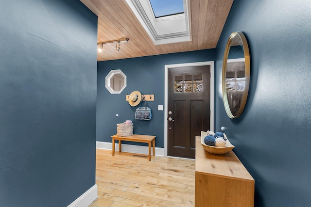 entrance foyer with light wood-style flooring, track lighting, a skylight, baseboards, and wood ceiling