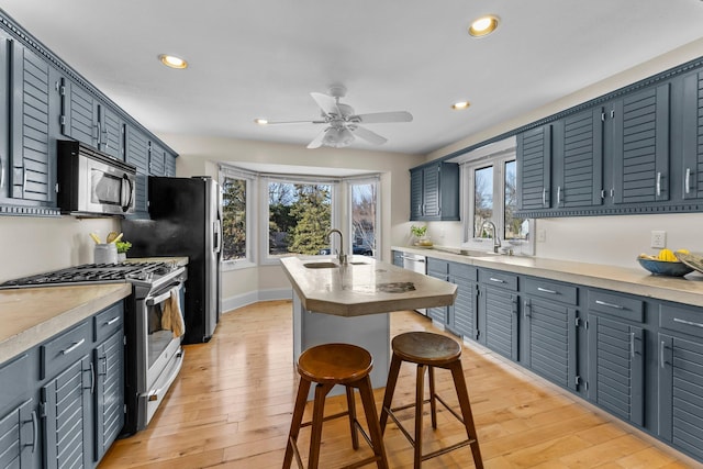 kitchen with a breakfast bar area, plenty of natural light, a sink, stainless steel appliances, and light wood-type flooring