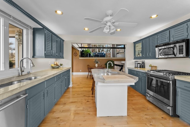 kitchen with a sink, a wealth of natural light, appliances with stainless steel finishes, and a kitchen island with sink