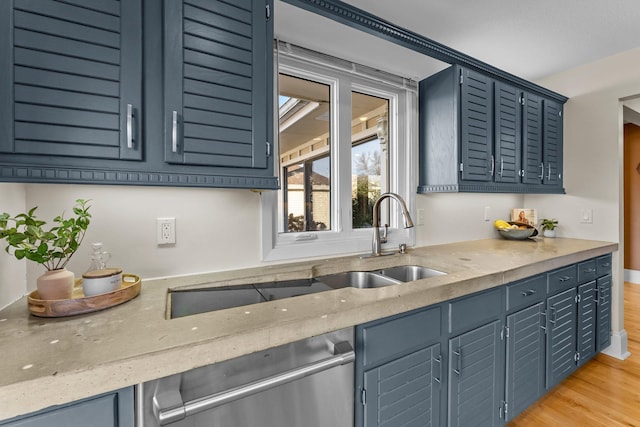 kitchen featuring a sink, light wood-type flooring, light stone countertops, and dishwasher