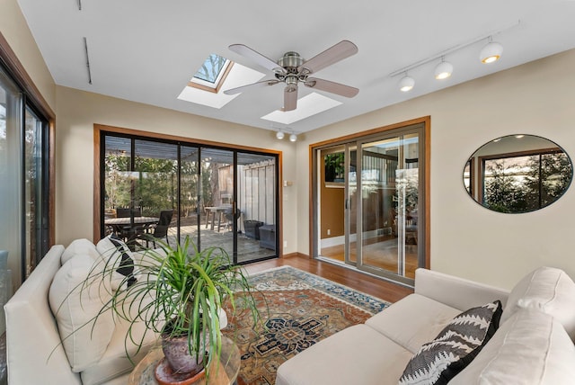 living area with a ceiling fan, a skylight, and wood finished floors