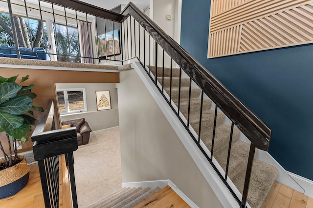 stairway with baseboards, a high ceiling, and wood finished floors