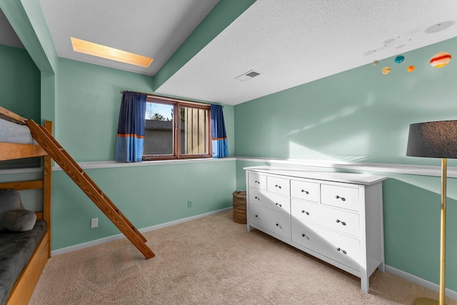 bedroom featuring light carpet, visible vents, a textured ceiling, and baseboards