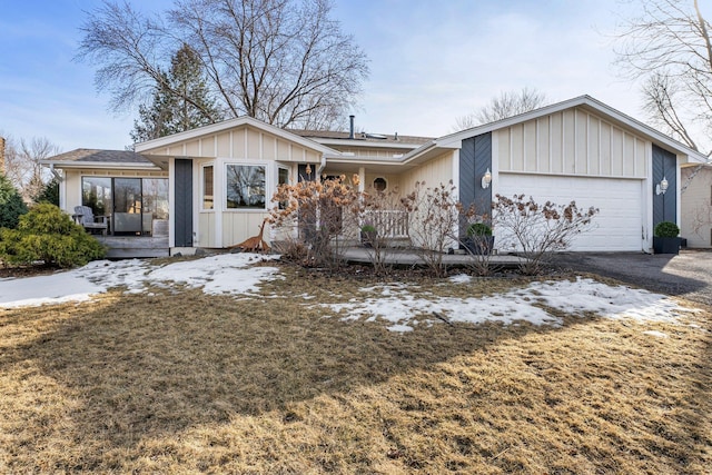 view of front of home with board and batten siding, an attached garage, covered porch, and driveway