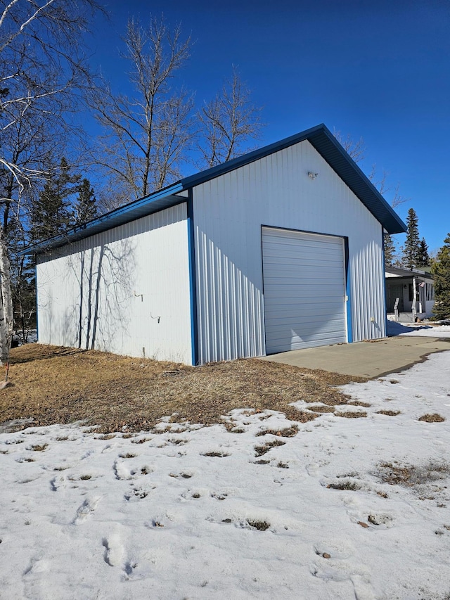 snow covered garage featuring a detached garage