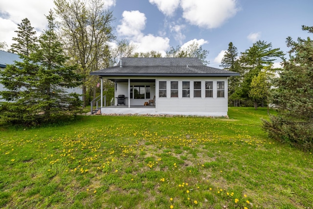 back of house with a shingled roof and a lawn