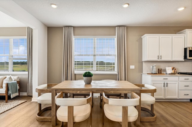 dining space with recessed lighting, baseboards, light wood-style flooring, and a textured ceiling