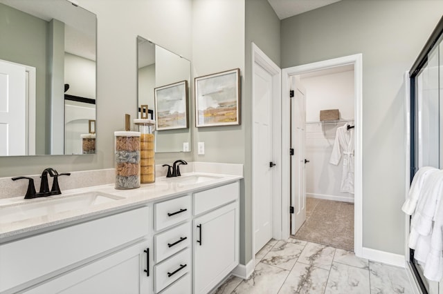 bathroom with marble finish floor, double vanity, a sink, and baseboards