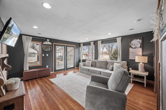 living room featuring recessed lighting, wood-type flooring, baseboards, and french doors