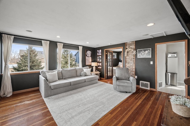 living room with hardwood / wood-style floors, attic access, visible vents, and baseboards