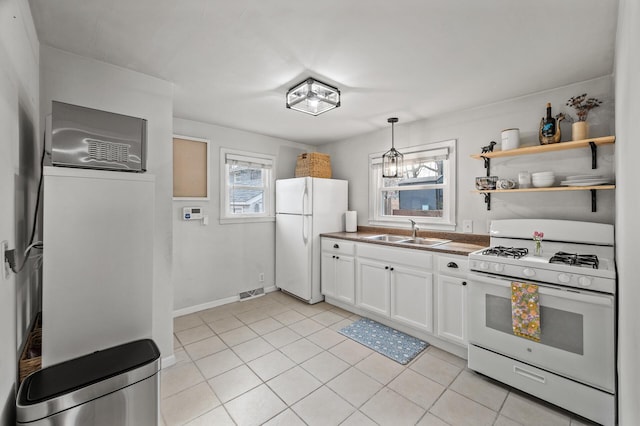 kitchen featuring light tile patterned floors, white appliances, a sink, visible vents, and white cabinetry