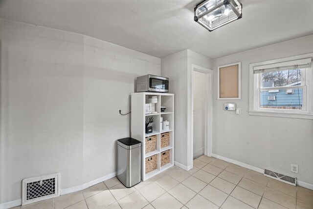 interior space featuring light tile patterned flooring, visible vents, and baseboards