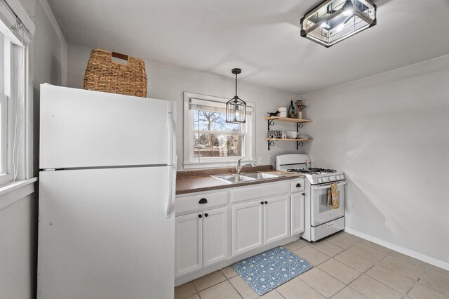 kitchen featuring white appliances, light tile patterned floors, hanging light fixtures, white cabinetry, and a sink