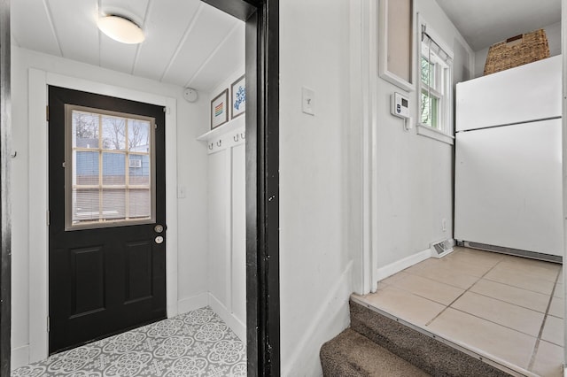 doorway to outside with light tile patterned flooring and baseboards