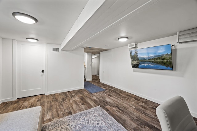 finished below grade area with baseboards, stairs, visible vents, and wood finished floors