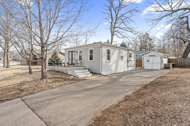 view of front facade featuring a storage shed, driveway, an outdoor structure, and fence