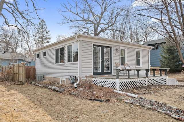 view of front of house with central AC unit, a wooden deck, fence, and french doors