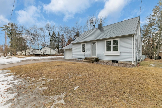 view of front facade featuring metal roof, a garage, concrete driveway, a chimney, and a front yard