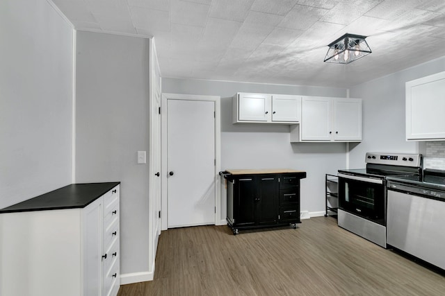 kitchen featuring baseboards, white cabinets, dark countertops, appliances with stainless steel finishes, and wood finished floors