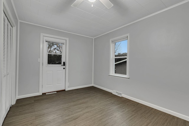 spare room with baseboards, crown molding, visible vents, and wood finished floors