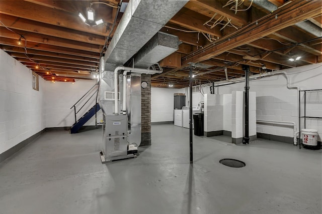 unfinished below grade area featuring independent washer and dryer, concrete block wall, visible vents, and heating unit