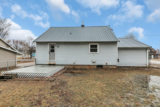 back of house featuring a deck, metal roof, and fence