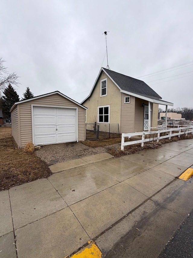 view of front of property featuring an outbuilding, fence, a detached garage, and stucco siding