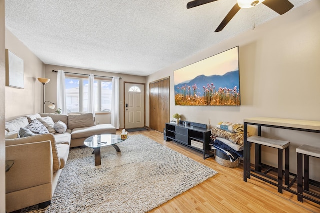 living room with a textured ceiling, ceiling fan, and wood finished floors