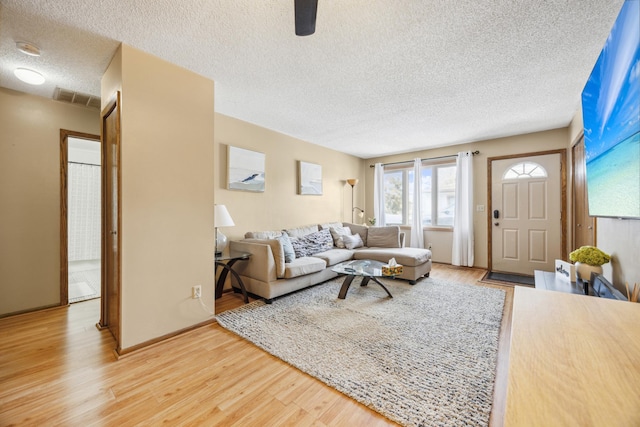 living area with visible vents, a textured ceiling, and light wood-style flooring