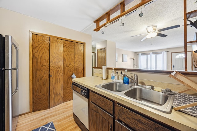 kitchen featuring light wood-type flooring, a sink, a textured ceiling, freestanding refrigerator, and dishwasher