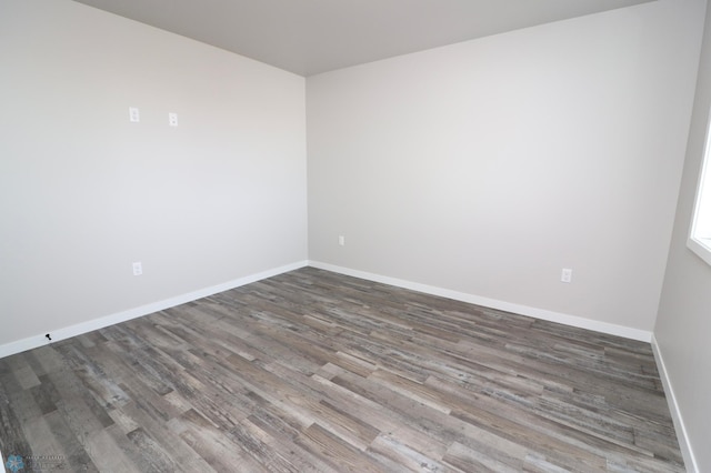 spare room with baseboards and wood finished floors