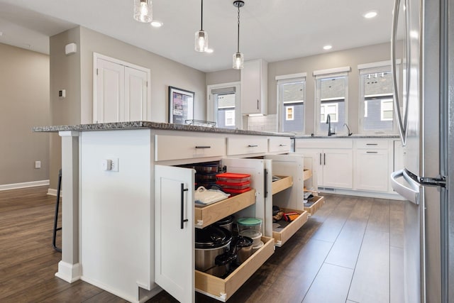 kitchen with white cabinetry, light stone counters, dark wood-style floors, and freestanding refrigerator