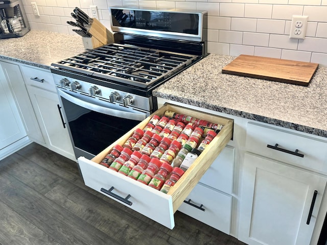 kitchen featuring decorative backsplash, white cabinets, dark wood finished floors, and stainless steel gas range oven