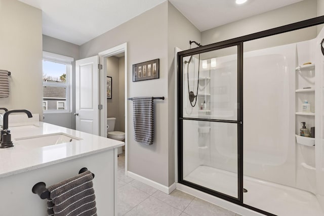 bathroom featuring baseboards, a sink, a shower stall, tile patterned floors, and toilet