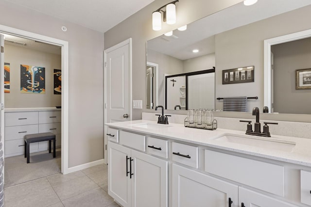 bathroom with tile patterned floors, double vanity, a stall shower, and a sink