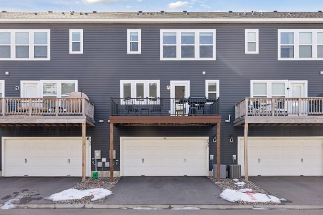 rear view of property featuring central air condition unit, a garage, and driveway