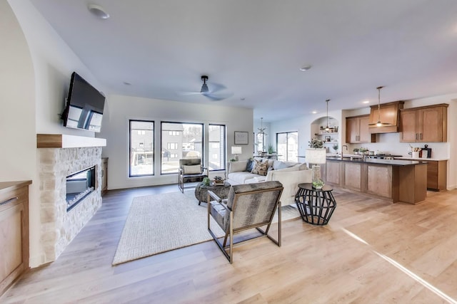 702 Summer Ave SE, New Prague, MN 56071 - living area with a stone fireplace, recessed lighting, light wood-type flooring, and ceiling fan