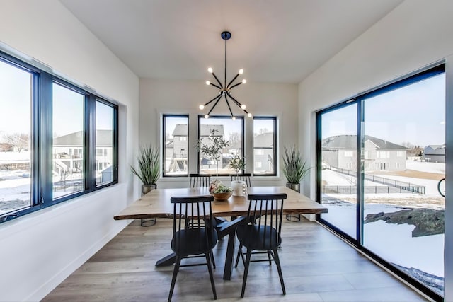 702 Summer Ave SE, New Prague, MN 56071 - dining room featuring a wealth of natural light, baseboards, light wood-style floors, and an inviting chandelier