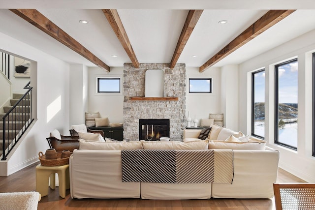 living room featuring stairs, a fireplace, plenty of natural light, and wood finished floors