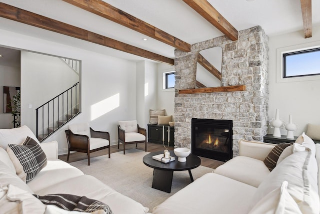 living room featuring plenty of natural light, a stone fireplace, and wood finished floors