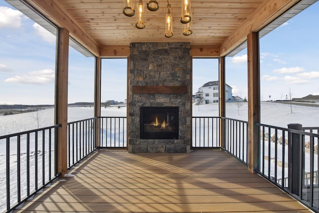 unfurnished sunroom featuring wooden ceiling, an outdoor stone fireplace, and a wealth of natural light