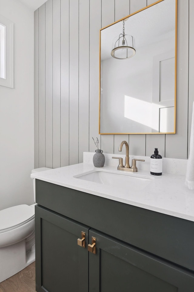 half bathroom featuring toilet, wood finished floors, and vanity