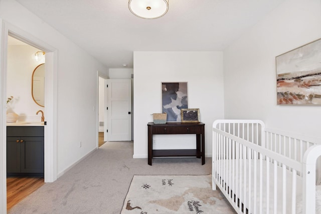 bedroom featuring carpet floors, a sink, baseboards, and ensuite bathroom