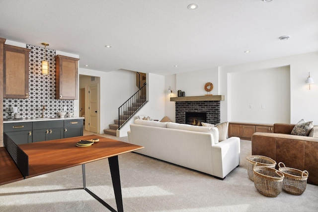 living area featuring light carpet, a brick fireplace, stairs, and recessed lighting