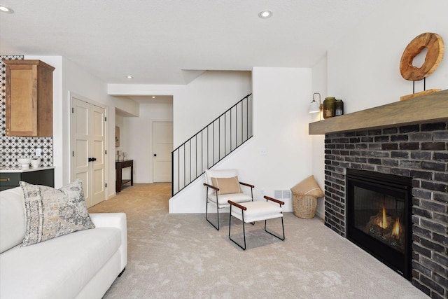 living area featuring light carpet, a brick fireplace, stairs, and recessed lighting