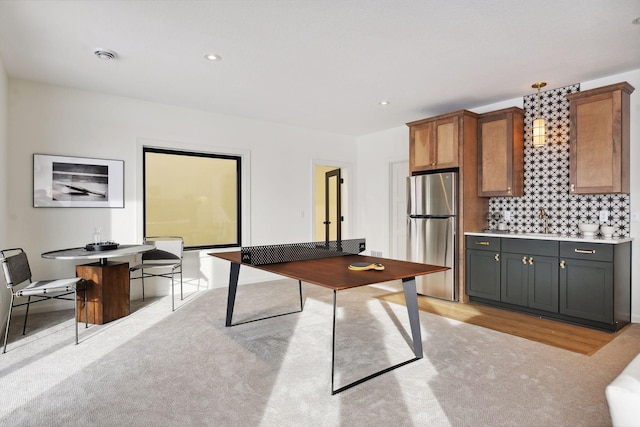 interior space with brown cabinetry, freestanding refrigerator, light countertops, backsplash, and recessed lighting