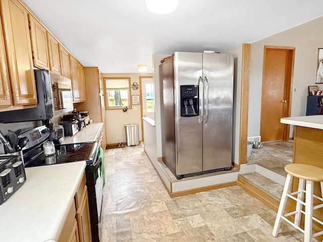 kitchen featuring stone finish floor, baseboards, stainless steel appliances, and light countertops